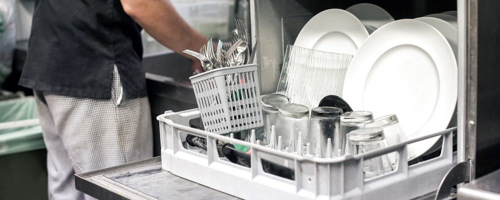 a kitchen employee unloads a one-tray commercial dishwasher