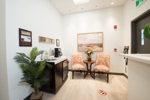 the reception area at haddon equipment head office with a coffee station, a framed photograph of the beach and fancy chairs with a vase of fresh flowers between them on a table
