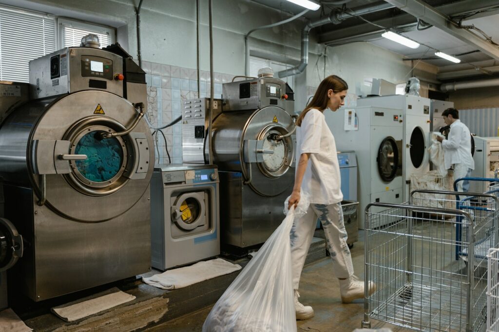 two young people do laundry with commercial laundry equipment in a large bc laundry facility