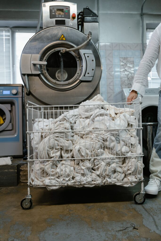 a man inspects a commercial washer as part of regular preventative maintenance on commercial laundry equipment