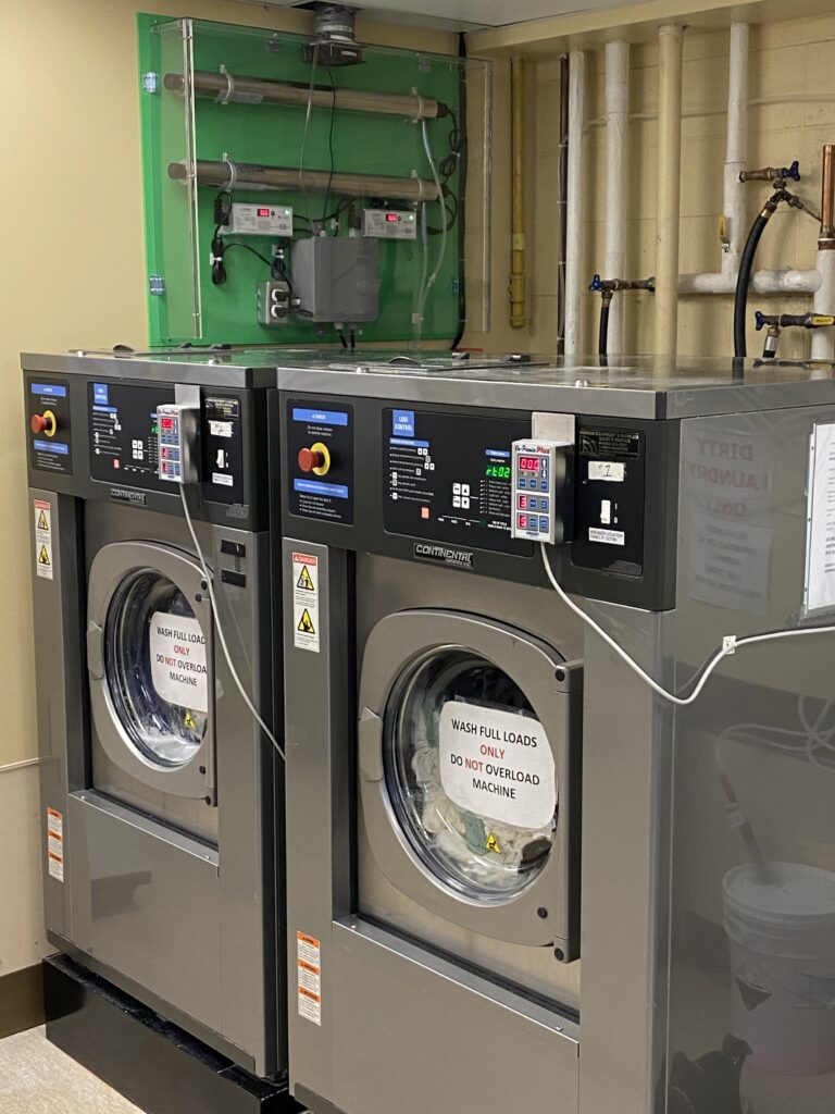 lux laundry system of two uv light tubes and a power box attached to two commercial washer extractors