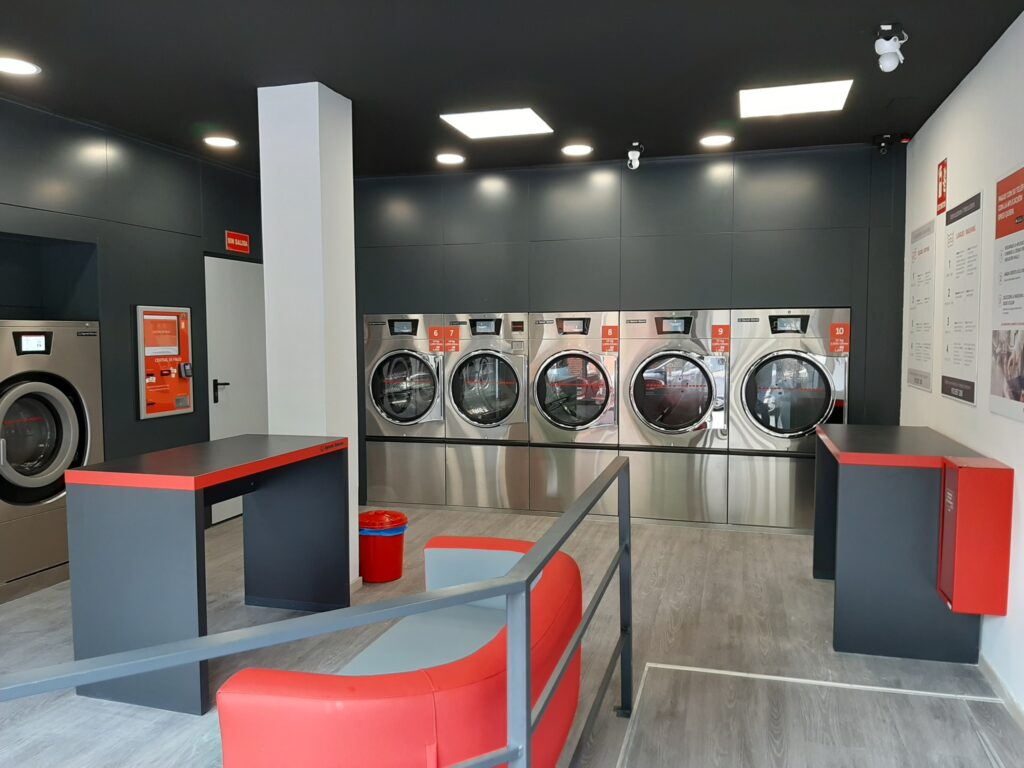 an ultra modern and comfortable laundromat in spain with a large couch and cleanly surroundings